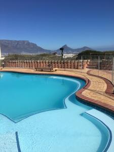 a swimming pool with blue water and a fence at 317 Neptunes Isle - Lagoon Beach in Cape Town