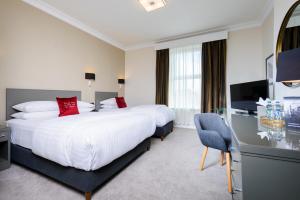 a hotel room with two beds and a television at The Metropole Hotel Cork in Cork