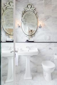 a bathroom with two mirrors and a sink and a toilet at The Metropole Hotel Cork in Cork