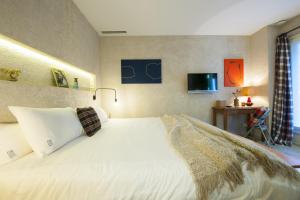 a bedroom with a white bed and a television at Kook Hotel Tarifa in Tarifa