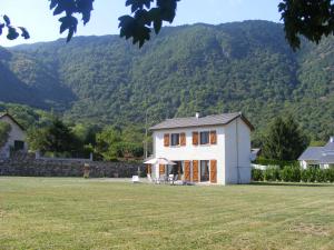 a house in a field with mountains in the background at La Résidence de Lorelei in Cierp