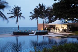 a swimming pool with a gazebo next to the ocean at Mövenpick Asara Resort & Spa Hua Hin in Hua Hin