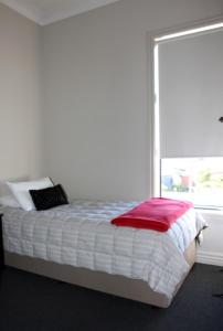 a bed with a red blanket and a window at Kaponga Hotel in Kaponga