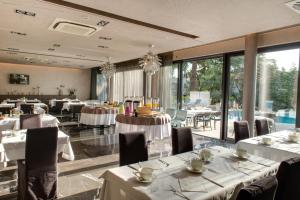 un restaurante con mesas y sillas blancas y ventanas en Hotel Arupinum en Rovinj