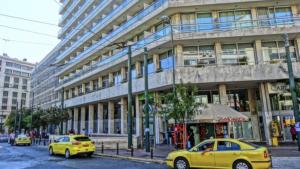 two yellow cars parked in front of a building at Athens central apartment in Athens