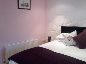 um quarto com uma cama com lençóis brancos e almofadas em Finn MacCools Public House & Guest Inn em Bushmills