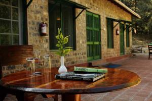 a wooden table with books and a vase on it at Fredy's Bungalow near Nainital in Bhīm Tāl