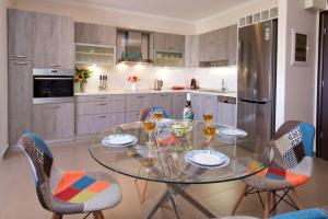 a glass table in a kitchen with chairs and wine glasses at K for Kefalonia in Karavomylos