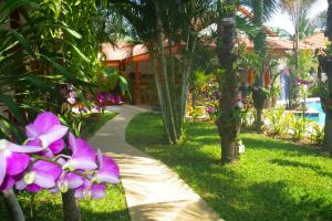 Un jardín con palmeras y flores moradas en una acera. en Mountain Beach Retreat, en Sam Roi Yot