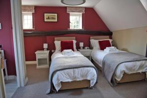 two beds in a attic room with red walls at The Three Horseshoes in Warham