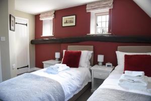 two beds in a room with red walls at The Three Horseshoes in Warham
