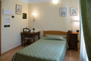 a small bedroom with a bed and a desk at Il Convento in Trino