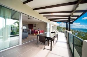 a dining room with a balcony overlooking the ocean at Whitsunday Reflections in Airlie Beach