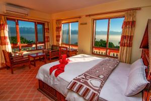 a bedroom with a bed and large windows at Peaceful Cottage & Cafe Du Mont in Nagarkot