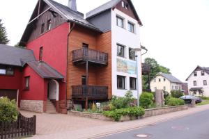 czerwono-biały dom z czarnym dachem w obiekcie Pension Danzer w mieście Oberhof