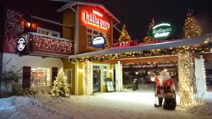 a woman and child standing outside of a restaurant with christmas lights at Hotel Hullu Poro in Levi