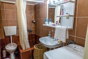 een badkamer met een wastafel, een toilet en een spiegel bij Next To The Sea - Apartment in Agia Triada