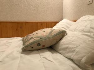 - un lit avec des draps blancs et un oreiller dans l'établissement Au pied du telecabine, T2 parking et casier a ski, à Cauterets