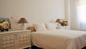 a bedroom with a large white bed with two lamps at Tavira Terrace in Tavira