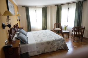a hotel room with a bed, chair, table and a lamp at Hostal La Posada in Torrellano