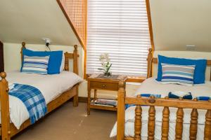 two beds in a bedroom with blue and white pillows at The Orange Bowl in Paarl