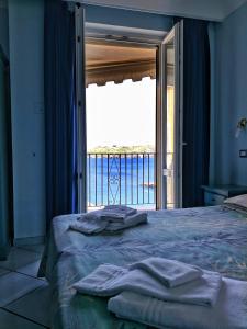 ein Schlafzimmer mit einem Bett und einem großen Fenster in der Unterkunft Hotel Mezzatorre in Ventotene