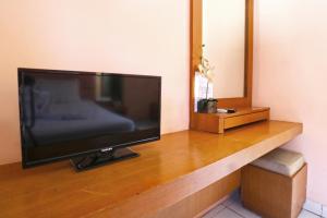 Une télévision à écran plat est installée au-dessus d'une table en bois. dans l'établissement Sayang Residence I, à Denpasar