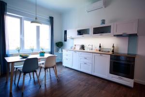 uma cozinha com armários brancos e uma mesa com cadeiras em Tkalcha4U em Zagreb