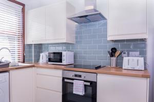 una cucina con armadi bianchi e piano cottura di Peebles House - Coorie Doon Apartments ad Ayr