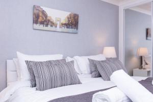 una camera da letto con un letto bianco con cuscini a righe di Peebles House - Coorie Doon Apartments ad Ayr