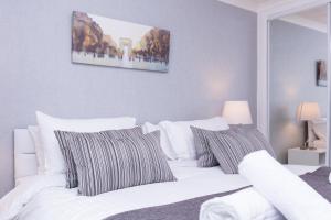 a bedroom with a white bed with striped pillows at Peebles House - Coorie Doon Apartments in Ayr