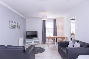 un soggiorno con divano, TV e tavolo di Peebles House - Coorie Doon Apartments ad Ayr