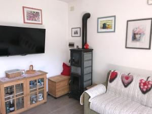 ein Wohnzimmer mit einem Flachbild-TV und einem Holzofen in der Unterkunft Almida in Castello di Fiemme