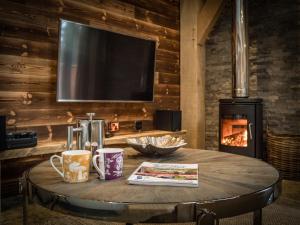 uma mesa com duas chávenas de café e uma televisão na parede em Macdui Lodge em Aviemore