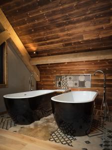 uma casa de banho com 2 banheiras num quarto com tectos em madeira em Macdui Lodge em Aviemore