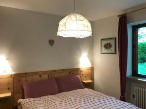 Schlafzimmer mit einem Bett und einem Kronleuchter in der Unterkunft Almida in Castello di Fiemme