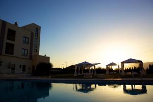 a pool in front of a building with a sunset at Hotel SJ in Tondela