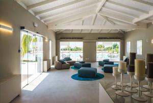 a living room with couches and chairs and windows at VOI Marsa Siclà Essentia in Sampieri
