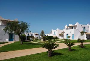 a row of white houses with palm trees in a yard at VOI Marsa Siclà Essentia in Sampieri