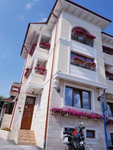 a white building with flower boxes and a motorcycle parked in front at Pensiunea Geostar in Curtea de Argeş