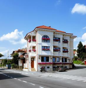 un edificio de apartamentos blanco al lado de una calle en Pensiunea Geostar, en Curtea de Argeş