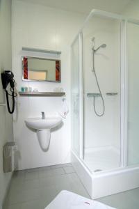 baño blanco con ducha y lavamanos en Hotel Olympia, en Kopřivnice