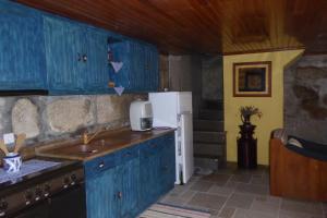 a kitchen with blue cabinets and a white refrigerator at Casa do Rio in Moita