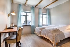 a bedroom with a bed and a desk and two windows at Englendingavík Homestay in Borgarnes