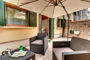 威尼斯的住宿－卡娜瑞格公寓- 威尼斯式公寓，天井配有两把椅子和一张桌子及遮阳伞