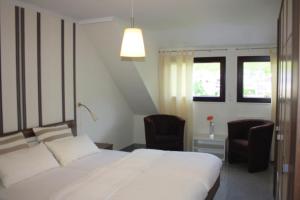 a bedroom with a large white bed and two chairs at Ferienwohnung Cella in Zell an der Mosel