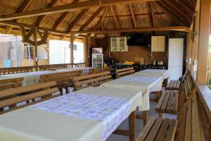 a room with four tables and benches and a kitchen at Cerdacul cu Stuf in Sfântu Gheorghe