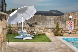 - un parasol blanc et des chaises à côté de la piscine dans l'établissement Villa Provenza, à Anafonítria