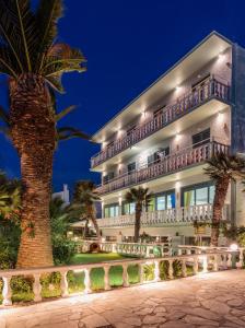 a large building with palm trees in front of it at Kokkari Beach Hotel in Kokkari