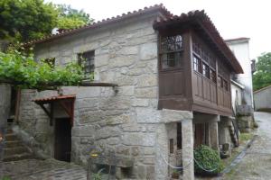 uma antiga casa de pedra com uma varanda numa rua em Casa do Rio em Moita